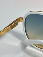 Louis Vuitton sunglasses close-up, gold-tone arms attached to white frame