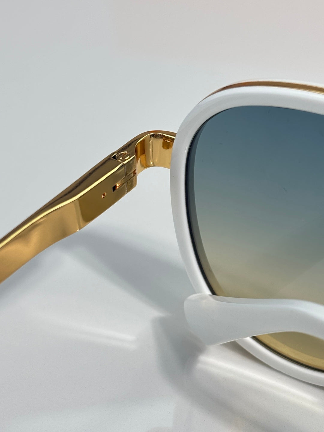 Louis Vuitton sunglasses close-up, gold-tone arms attached to white frame