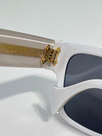 Gucci glasses close-up: white frame with gold hinge detail and dark lens area