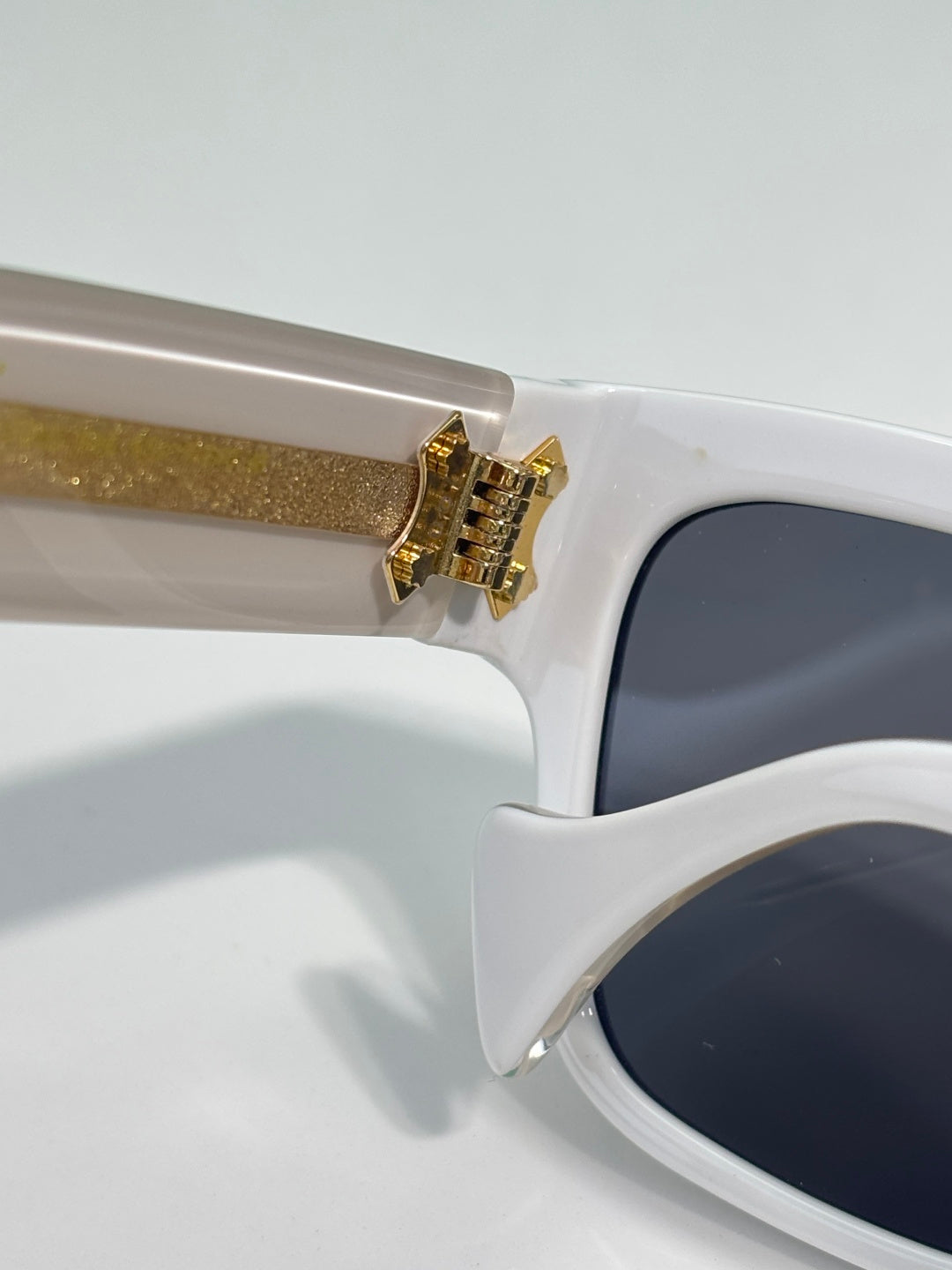 Gucci glasses close-up: white frame with gold hinge detail and dark lens area