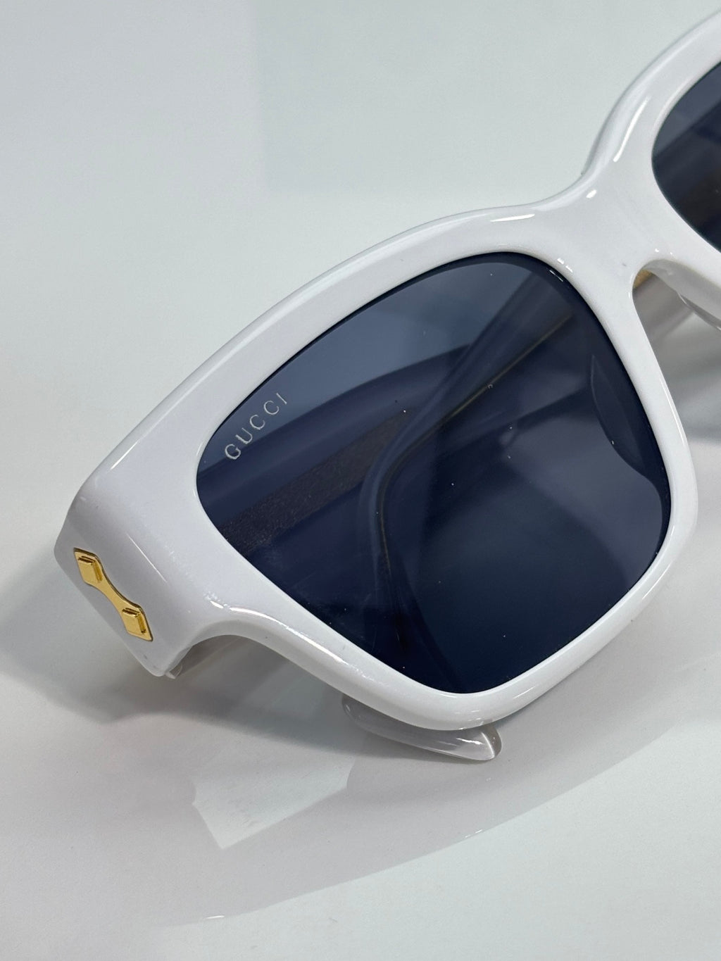 Gucci glasses close-up: white cat-eye frame with dark navy-tinted lenses