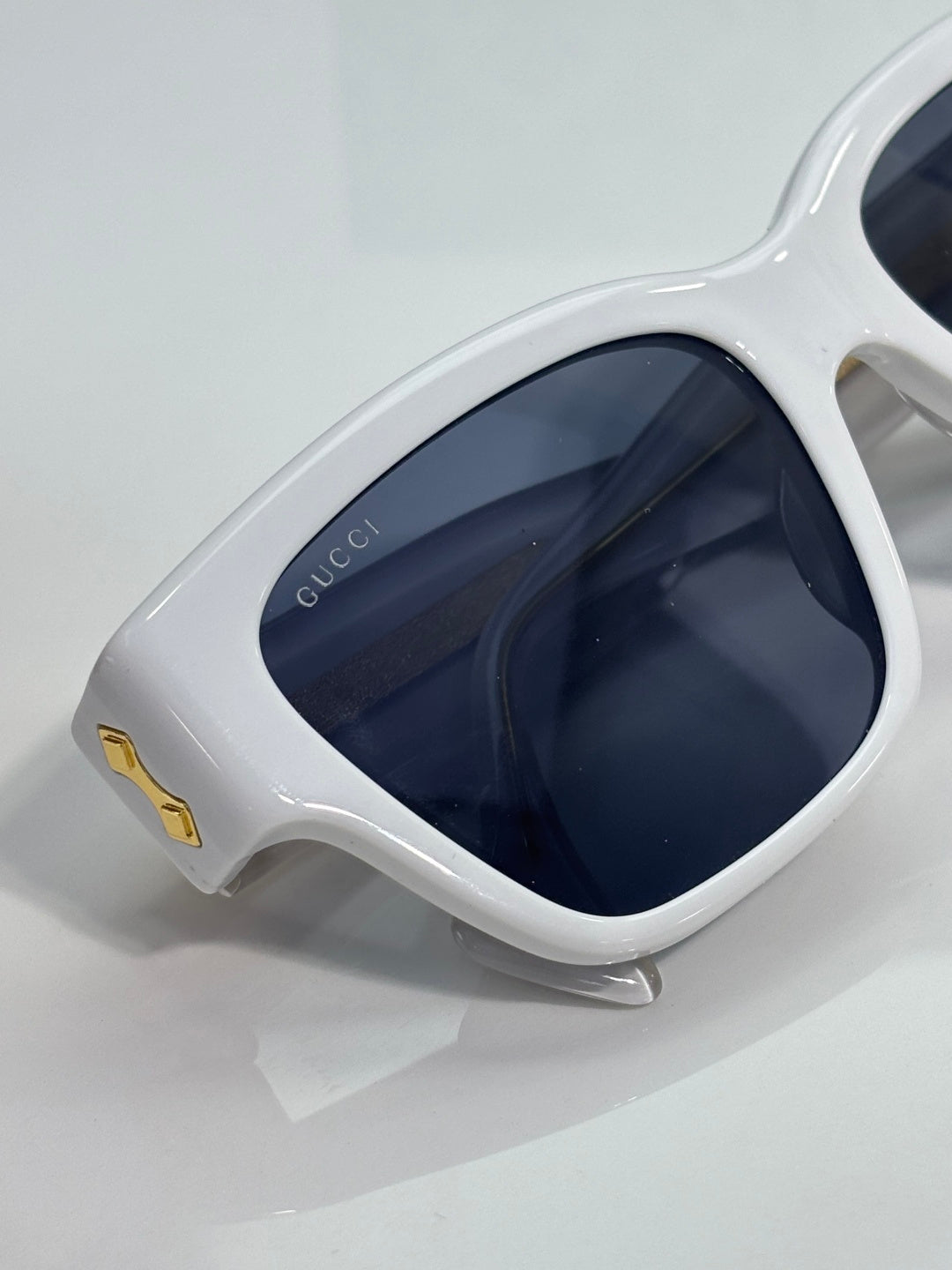 Gucci glasses close-up: white cat-eye frame with dark navy-tinted lenses