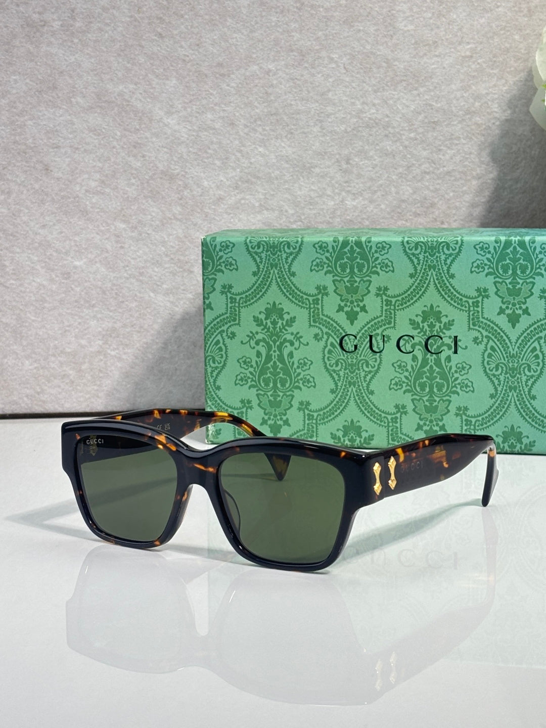 Gucci glasses with dark frame and green-tinted lenses, gold temple details