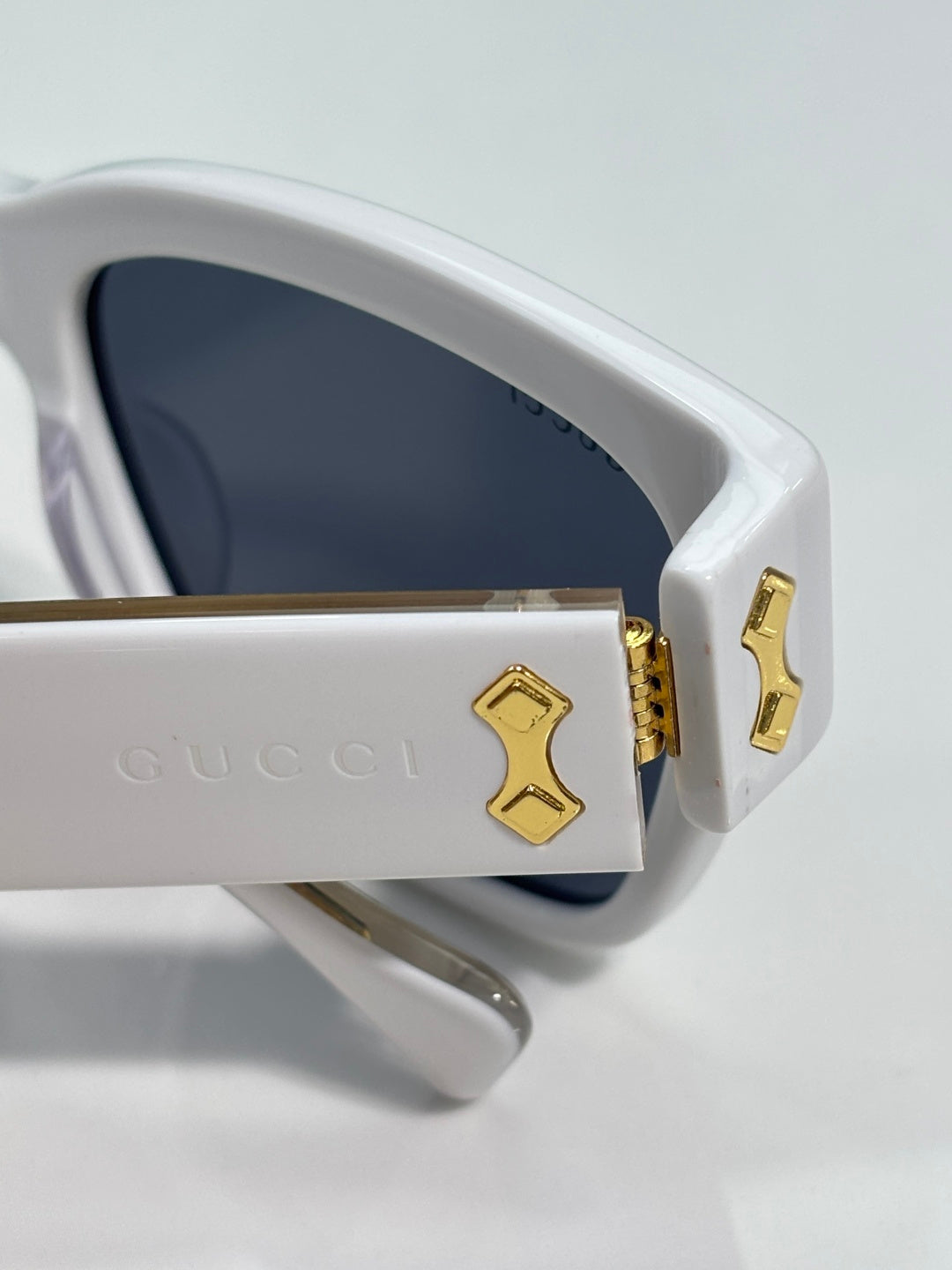 Gucci glasses close-up of side logo plate, white frame with dark lenses