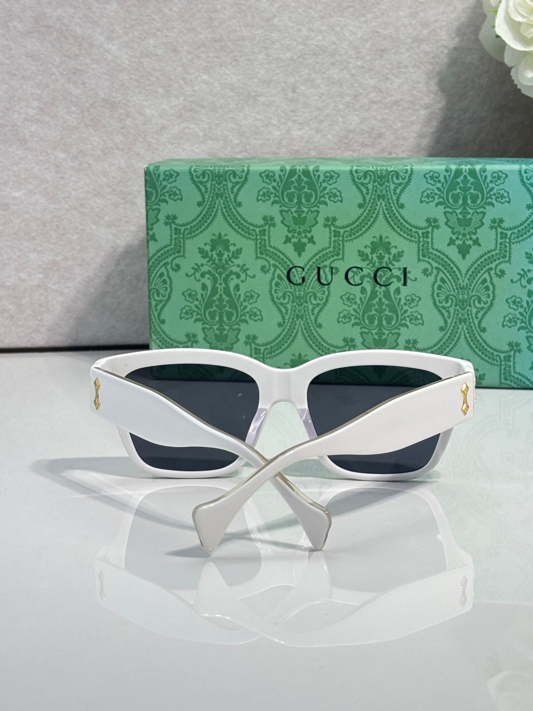 Gucci glasses with white cat-eye frame, dark lenses, and gold side accents