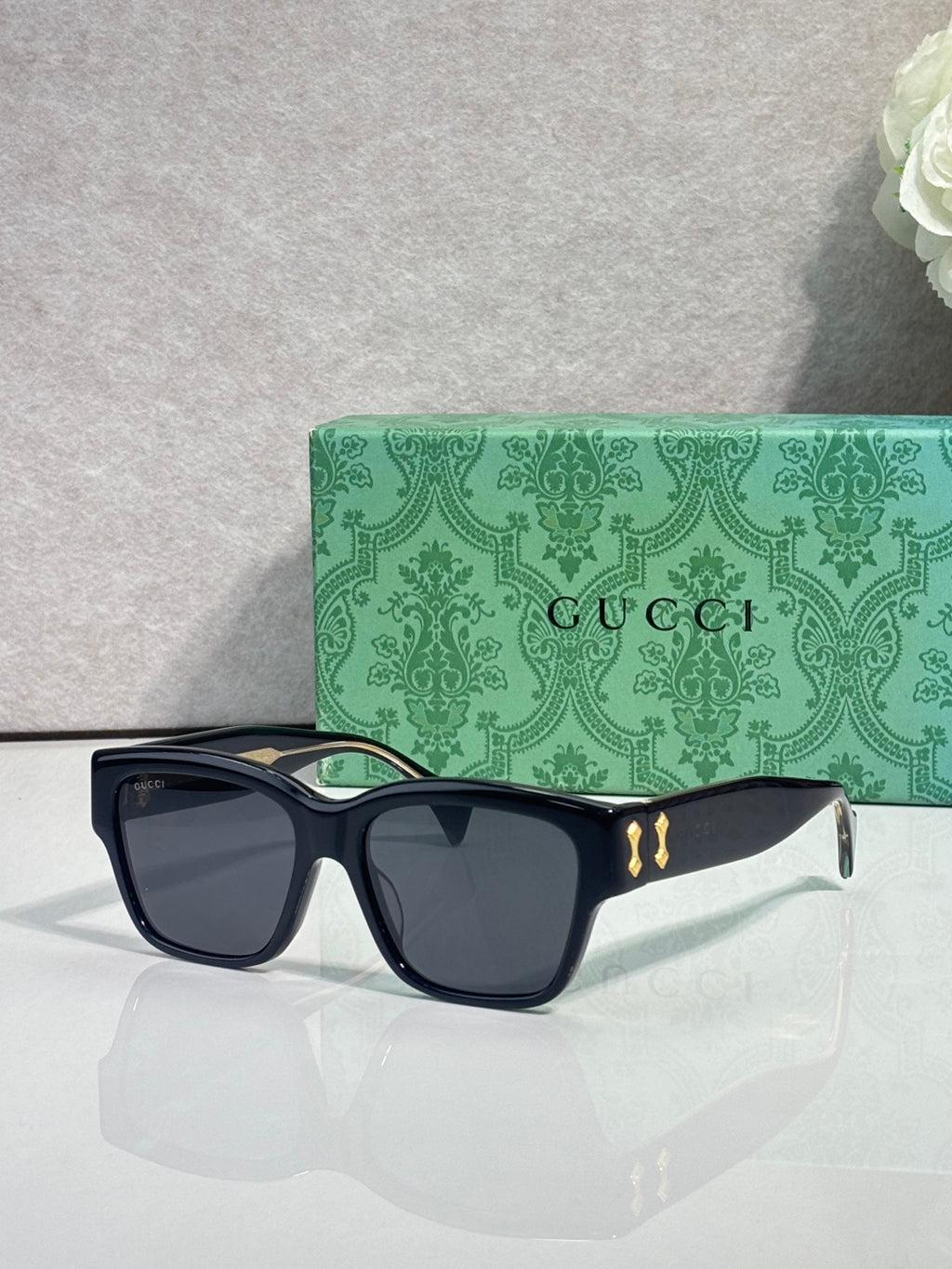 Gucci glasses with dark frame and dark lenses, gold emblem on the front