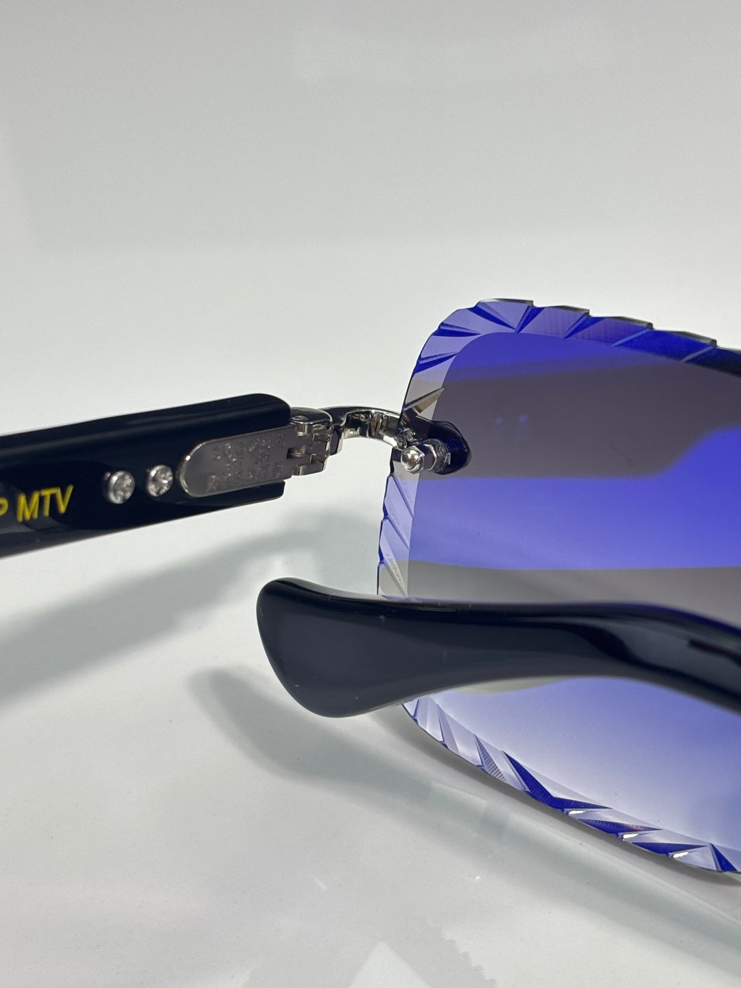 Chrome sunglasses side view with blue temple detailing and dark tinted lens surface