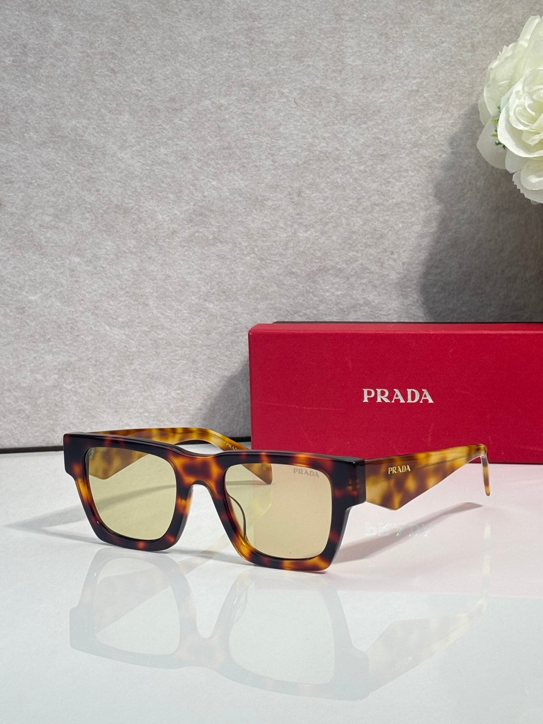Prada glasses with tortoiseshell frame and amber tinted lenses, with red case