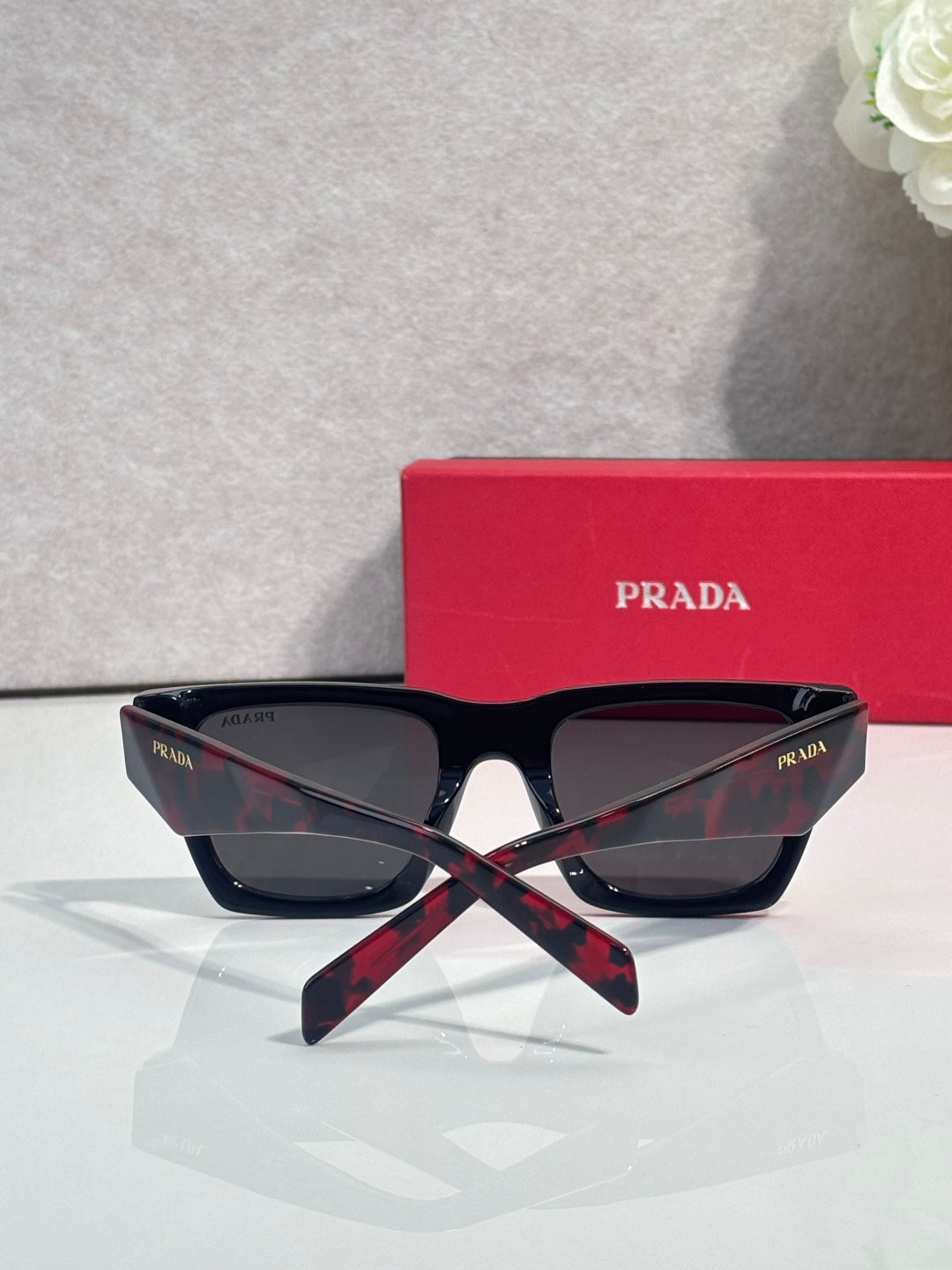 Prada glasses with dark frame and dark lenses, with red case