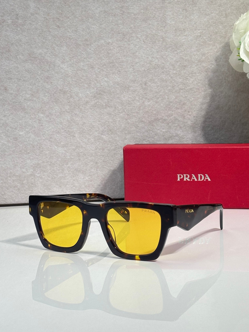 Prada glasses with black frame and yellow tinted lenses, with red case