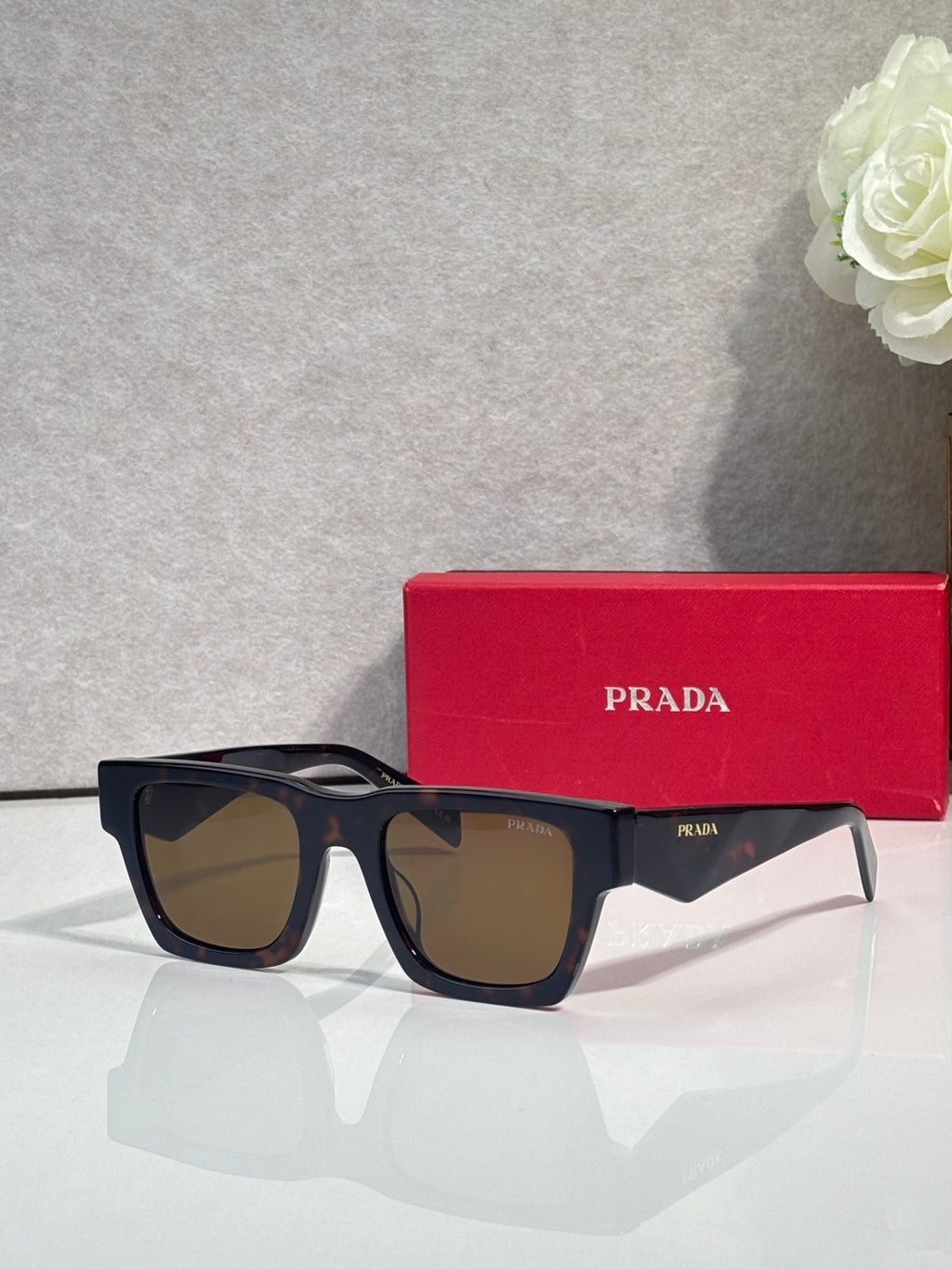 Prada glasses with dark frame and black tinted lenses, with red case