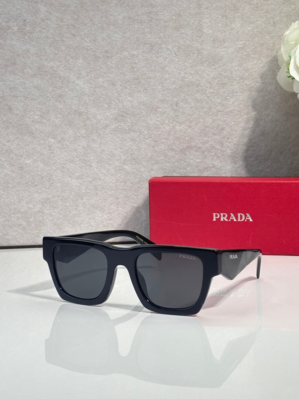 Prada glasses with dark blue frame and dark tinted lenses, with red case