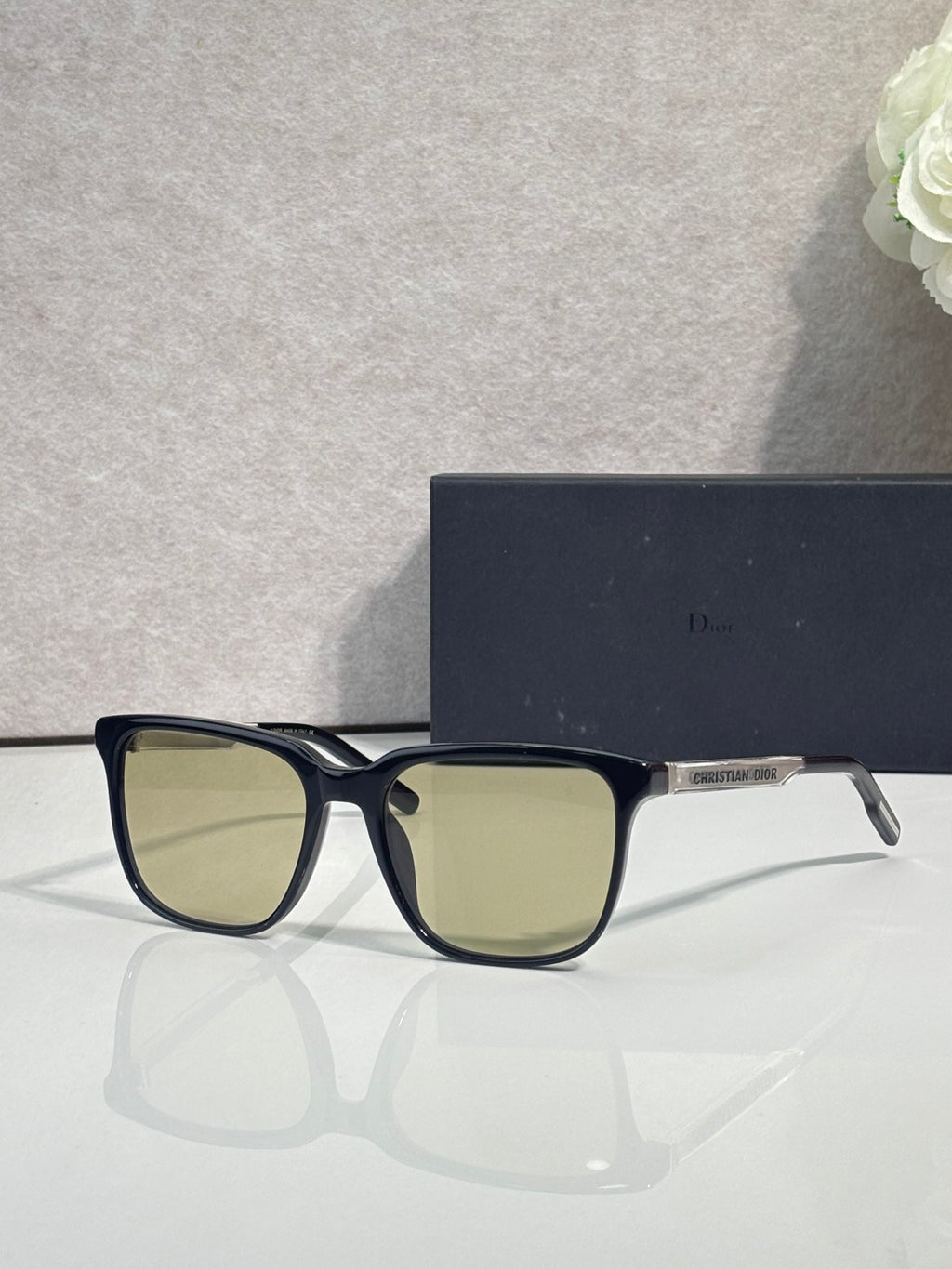 Sunglasses with black frame and light green tinted lenses.