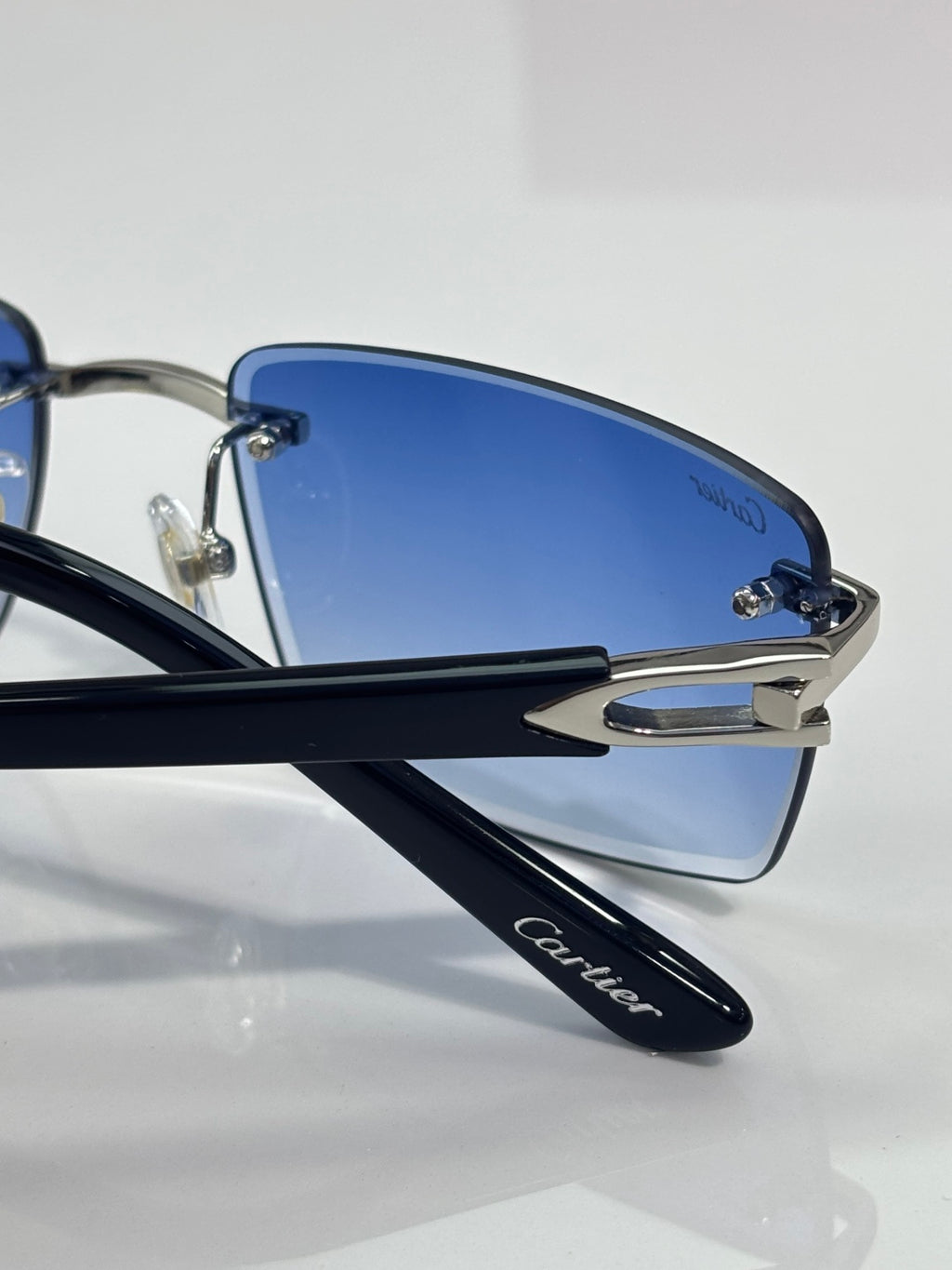 Blue lens sunglasses with black temples and metal hinges labeled Cartier