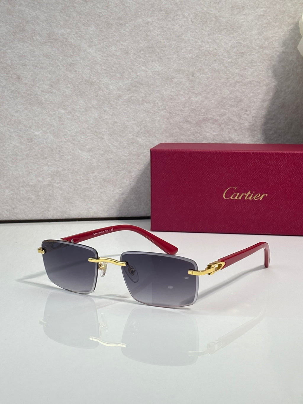 Gold sunglasses with dark gray lenses and red temple accents
