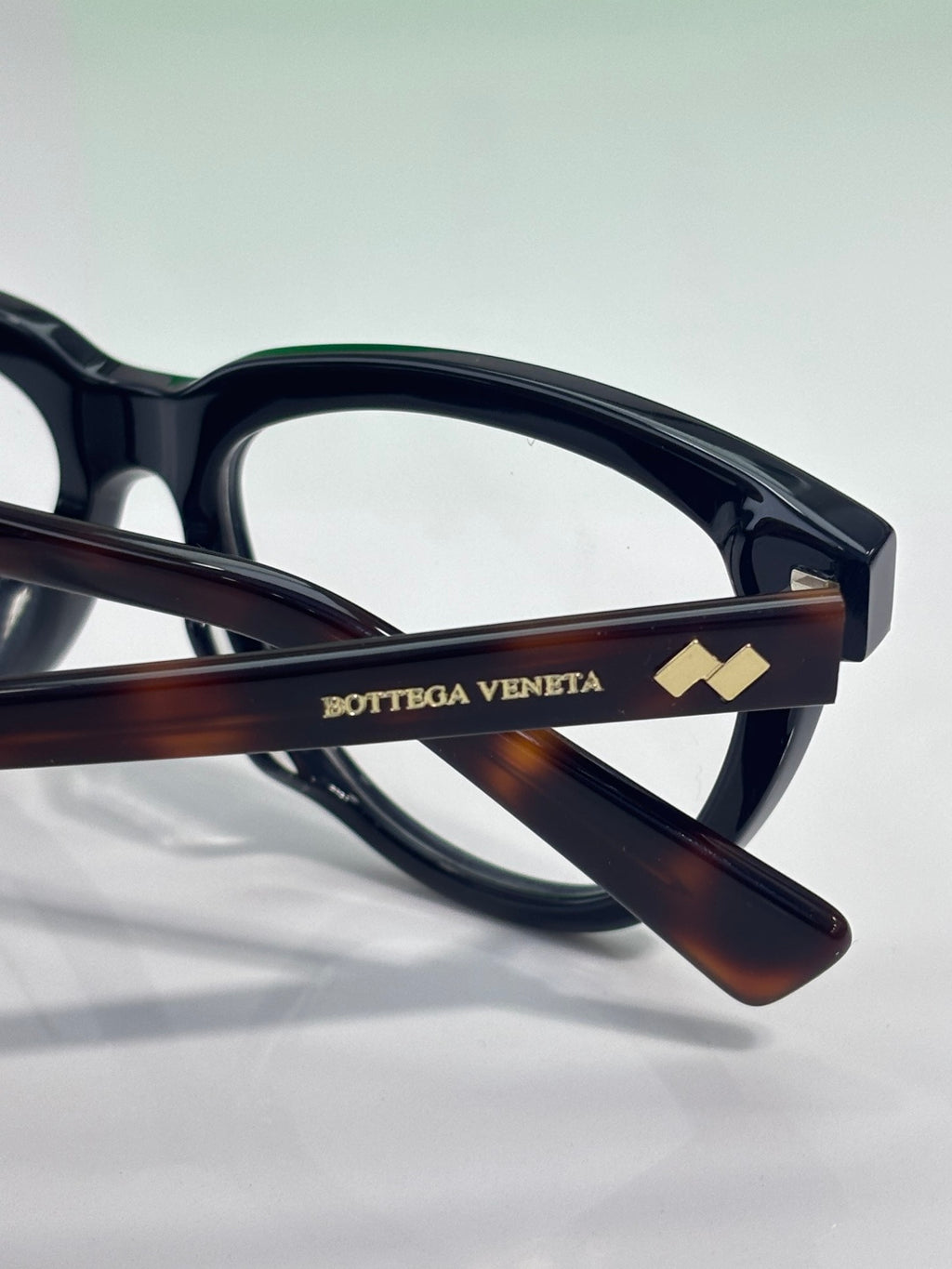 Bottega Veneta eyeglasses temple close-up, tortoise arm with logo detail