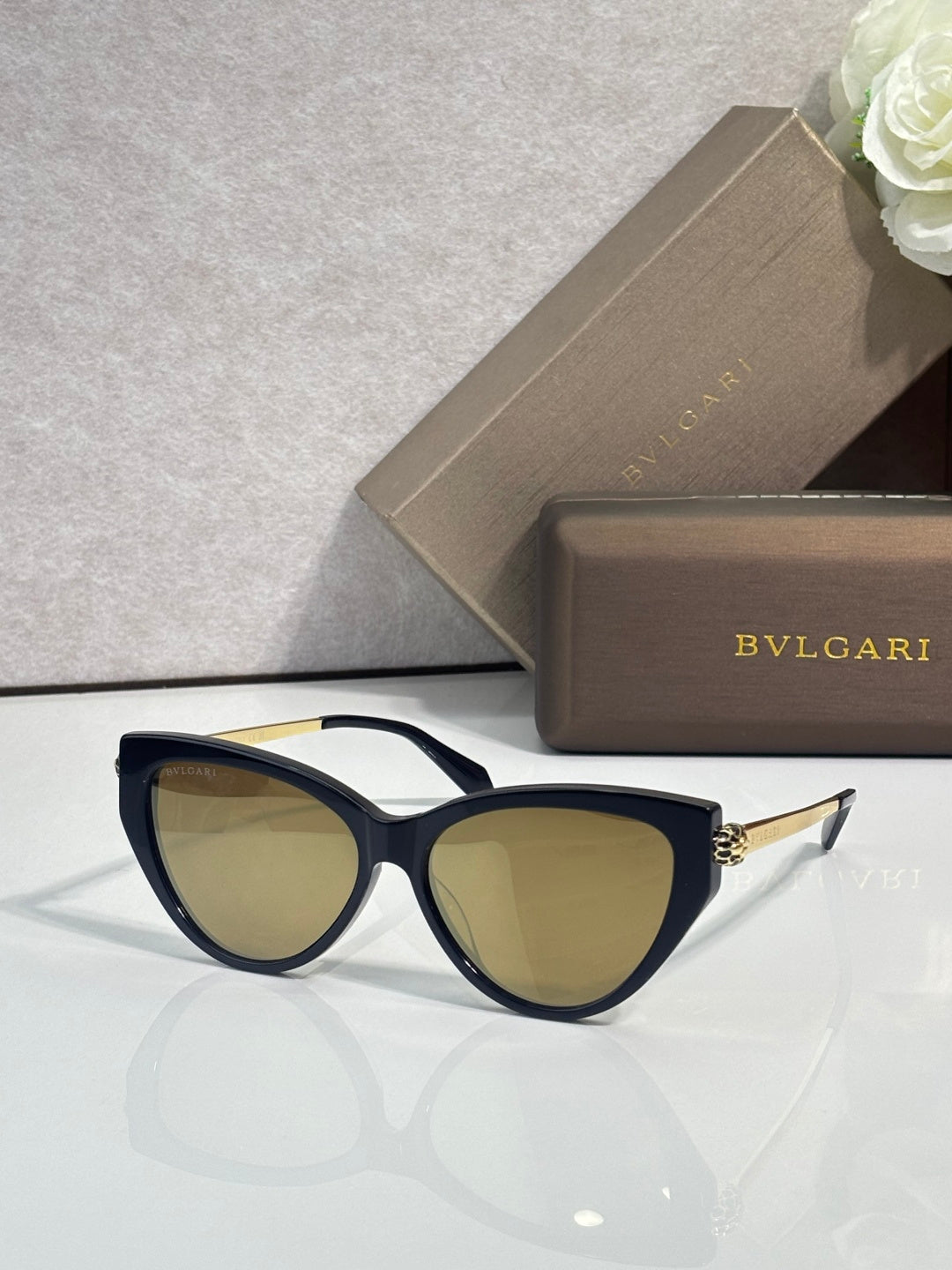 Black cat-eye sunglasses with warm tinted lenses and gold-tone temple accents.