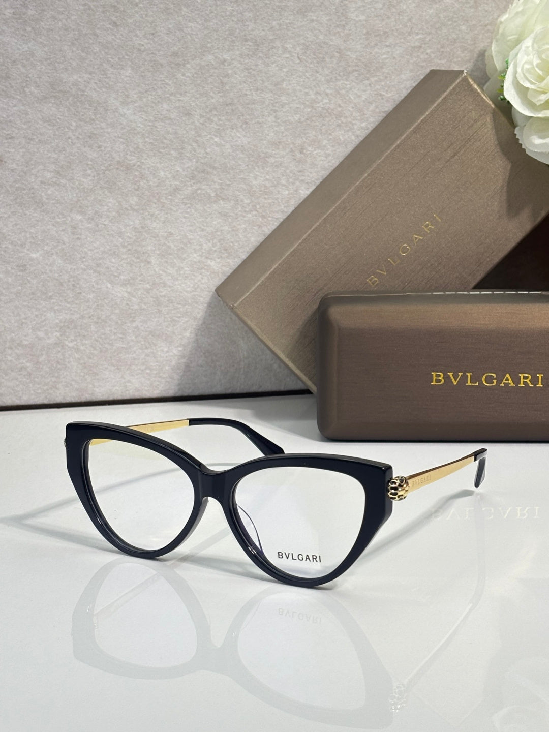 Black cat-eye eyeglasses with clear lenses and gold-tone temple accents.