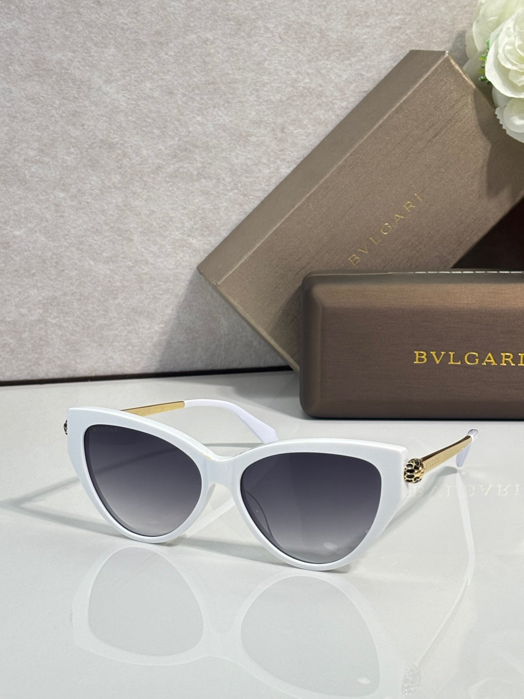 White cat-eye sunglasses with dark tinted lenses and gold-tone temple accents.