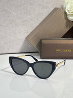 Black cat-eye sunglasses with dark tinted lenses and gold-tone hinge details.