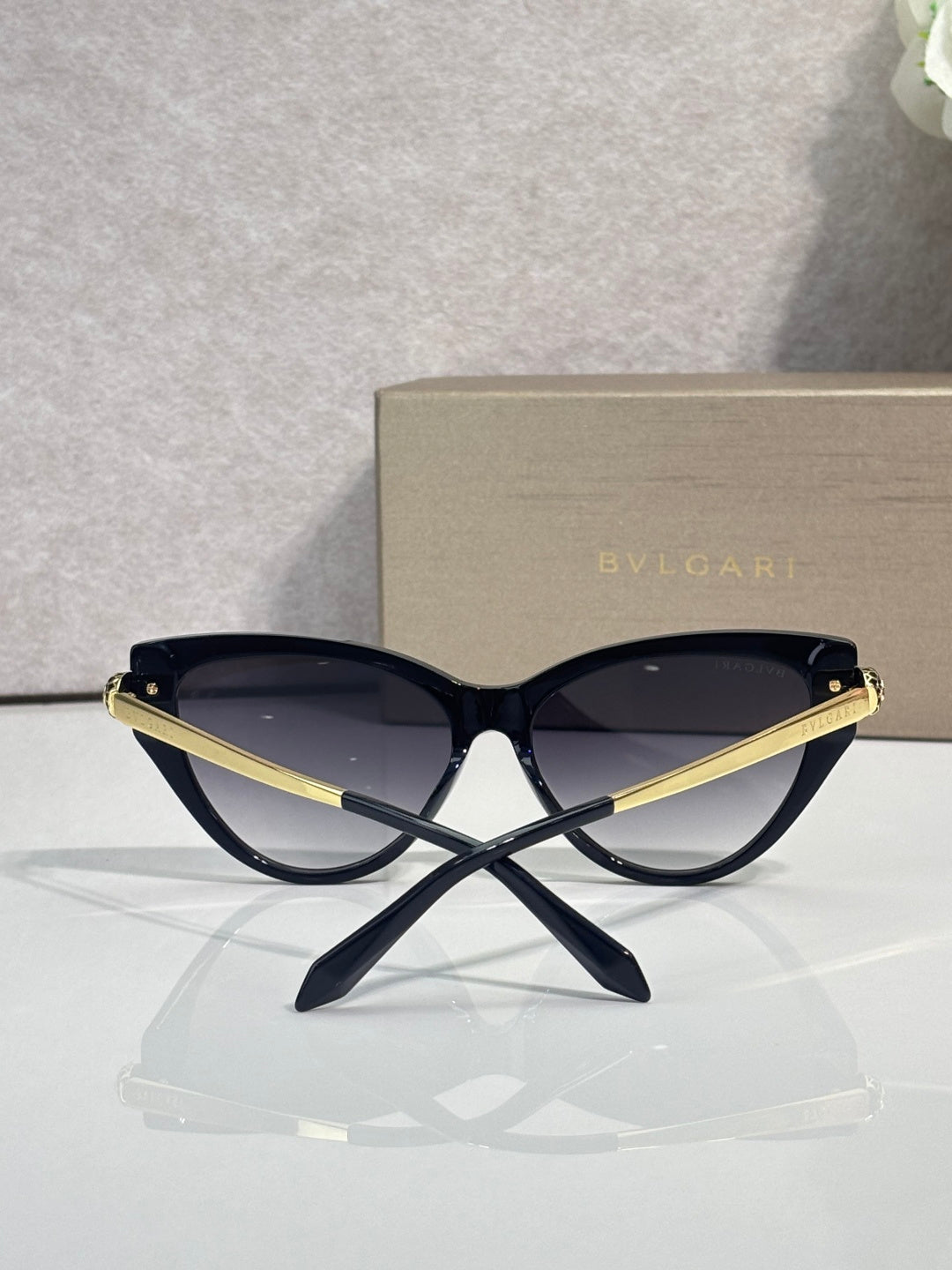 Cat-eye sunglasses with dark navy frames, gold accents, and tinted lenses