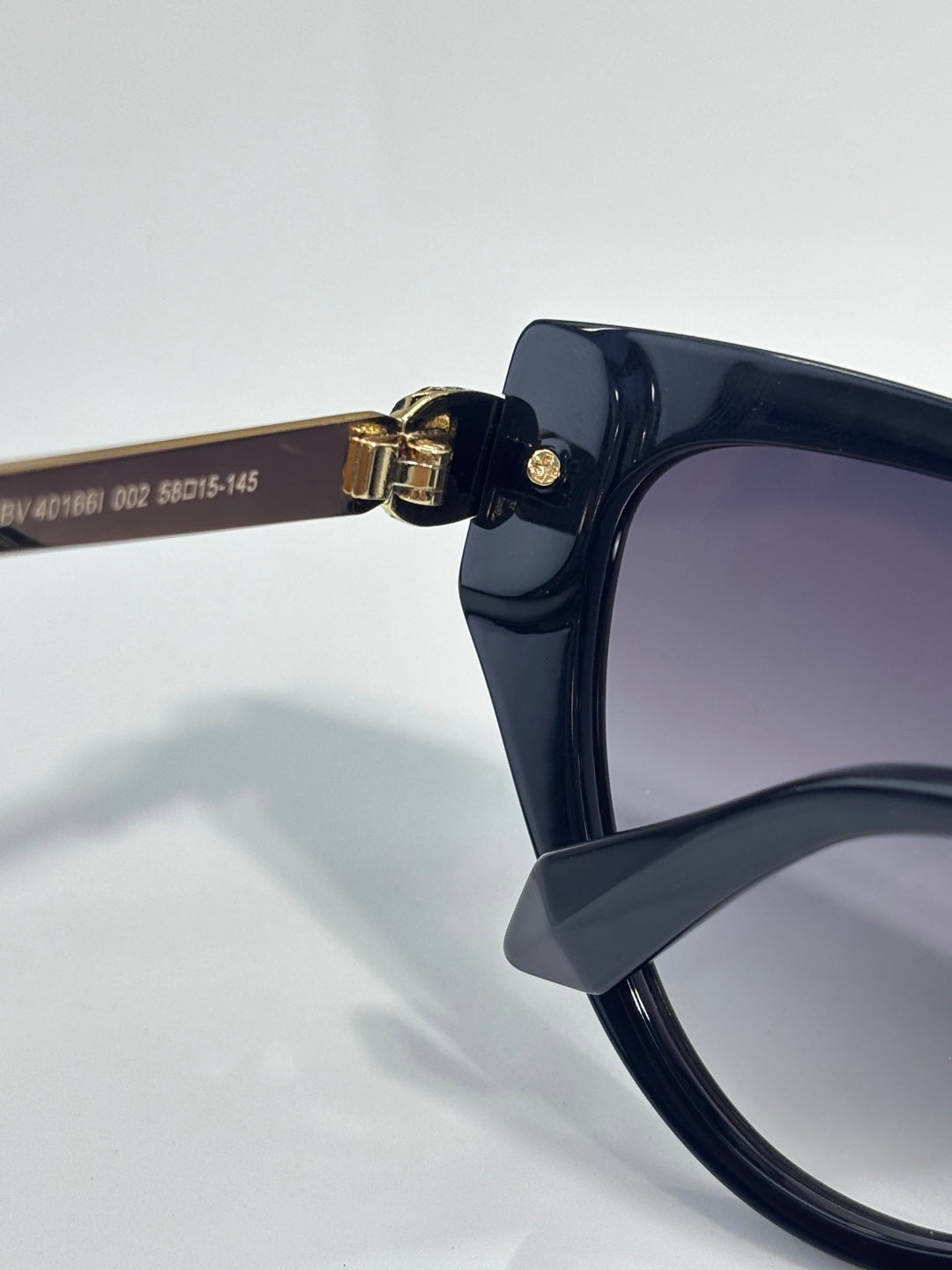 Cat-eye sunglasses with dark navy frame and gold hinge at the temple, tinted lenses