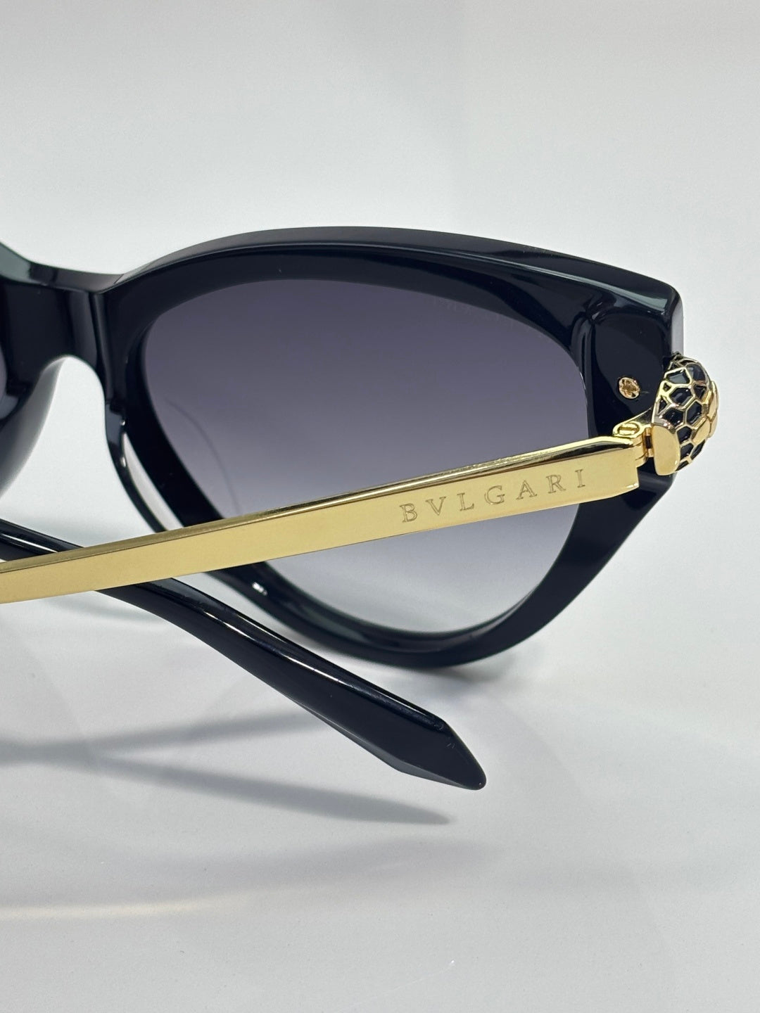 Cat-eye sunglasses with dark navy front, gold BVLGARI bar detail, tinted lenses