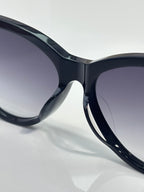 Close-up of cat-eye sunglasses with glossy dark navy frames and gradient tinted lenses