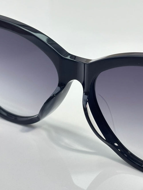 Close-up of cat-eye sunglasses with glossy dark navy frames and gradient tinted lenses