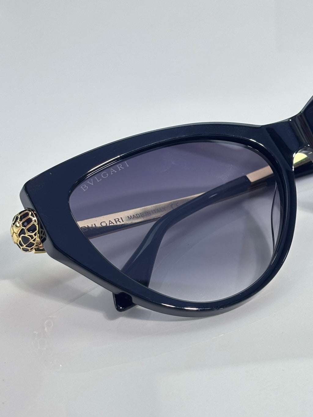 Cat-eye sunglasses with dark navy frames and gold clasp on the temple, tinted lenses