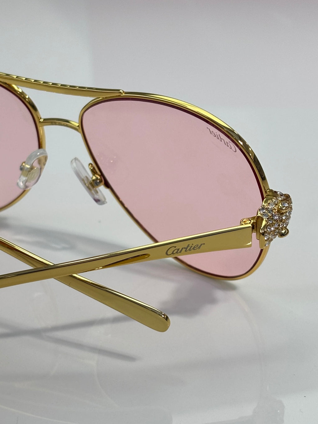 Cartier sunglasses close-up with pink tinted lenses and gold-tone cat-eye frame detail