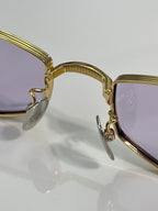 Close-up of gold metal glasses frame, hinge, and clear lens