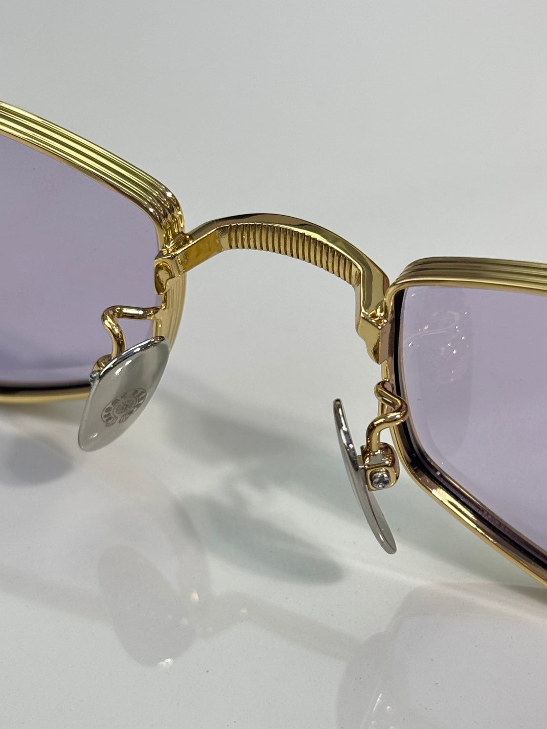 Close-up of gold metal glasses frame, hinge, and clear lens