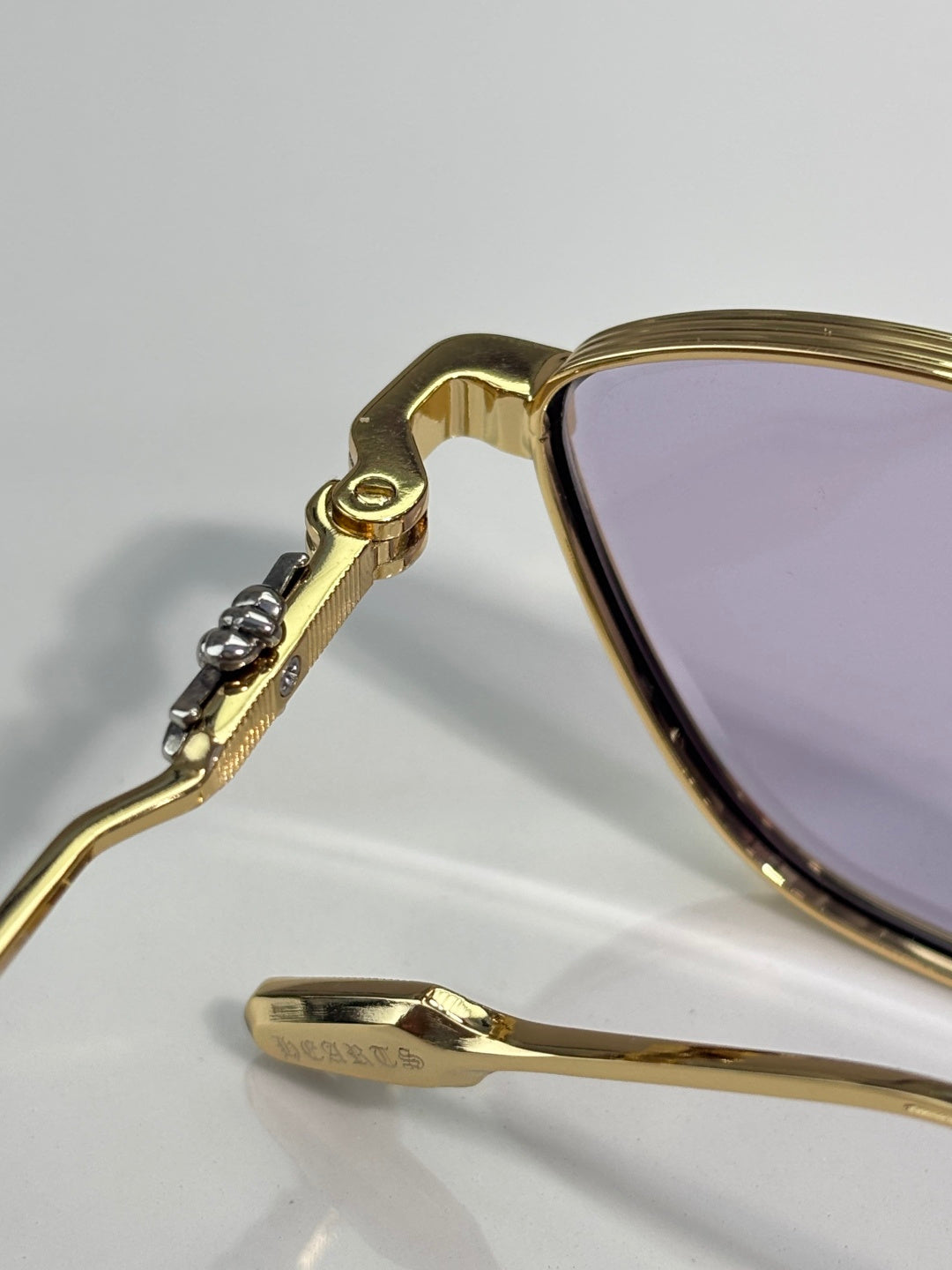 Gold temple hinge with small stones detail and purple-tinted lens edge