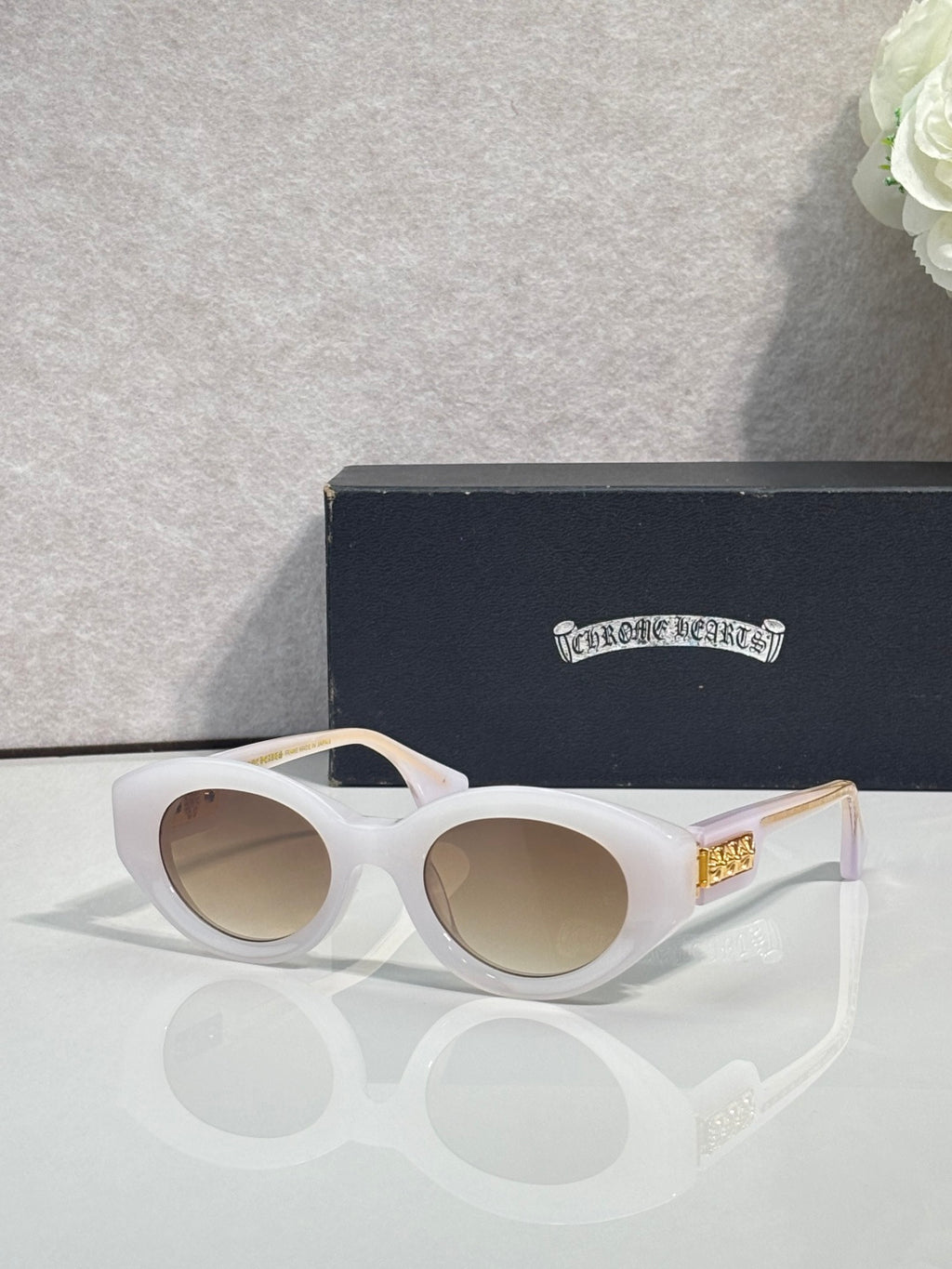 White round-frame glasses with tinted lenses and gold detail on temple