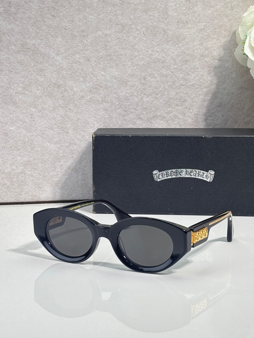 Black round-frame glasses with tinted lenses and gold detail on temple