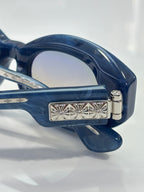 Close-up of navy glasses hinge with decorative metal plate and circular rivet