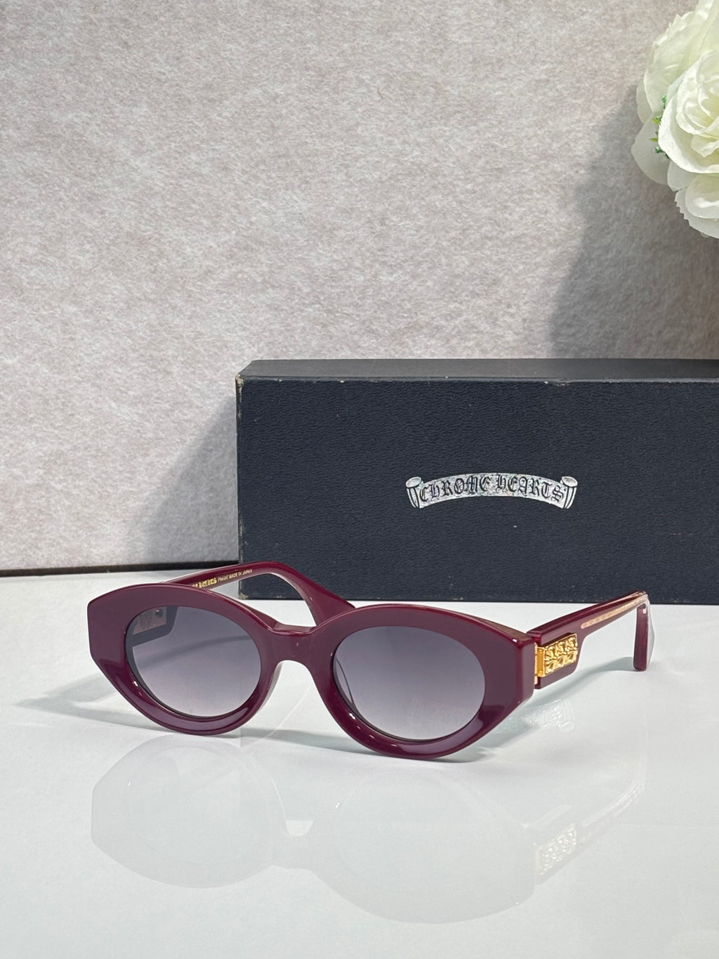 Burgundy round-frame glasses with tinted lenses and gold detail on temple
