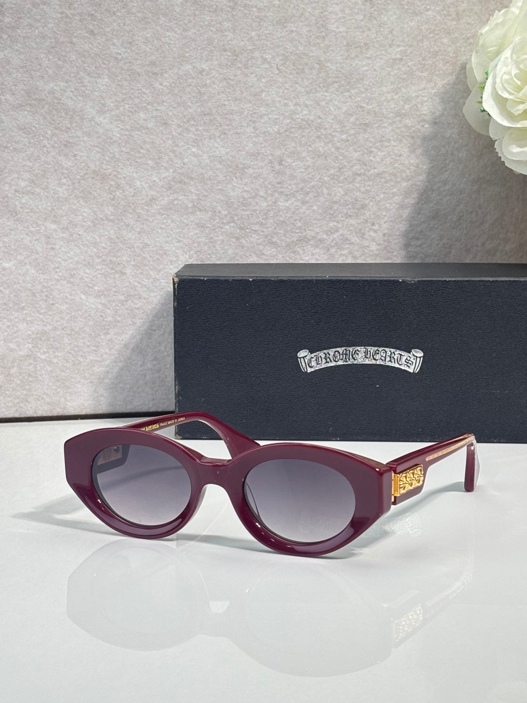 Burgundy round-frame glasses with tinted lenses and gold detail on temple