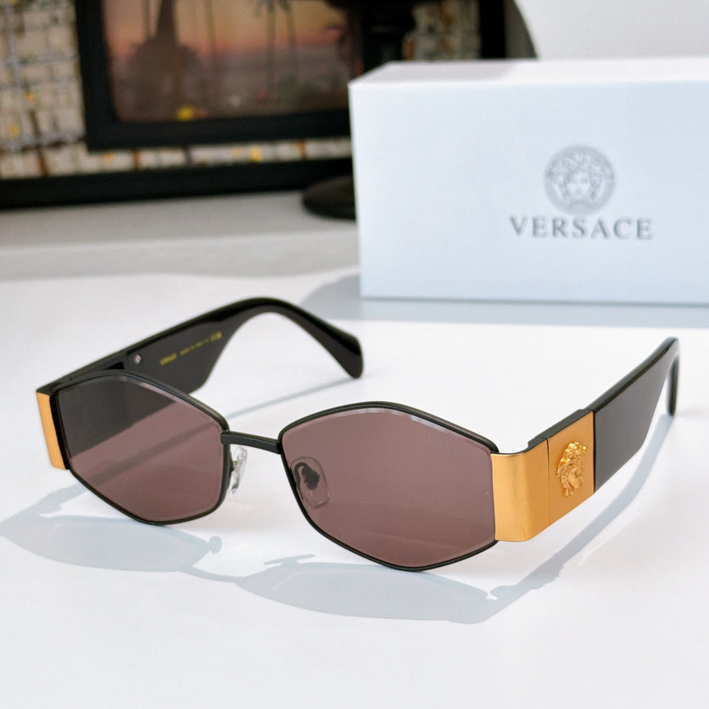 Cat-eye sunglasses with gold-tone frame, rose-tinted lenses, and black temples with logo detail.