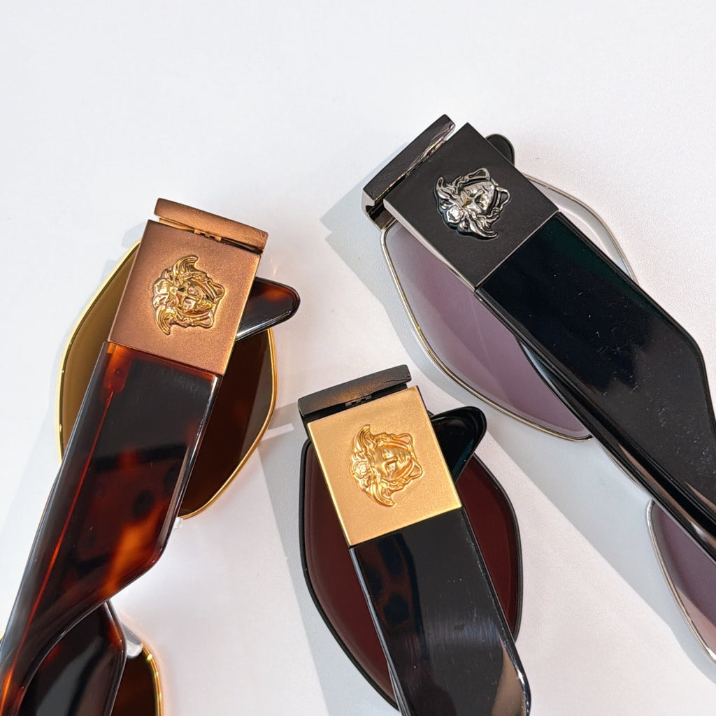Sunglasses temple tips and frames with gold logo emblems on dark and tortoise-look styles.
