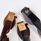 Sunglasses temple tips and frames with gold logo emblems on dark and tortoise-look styles.