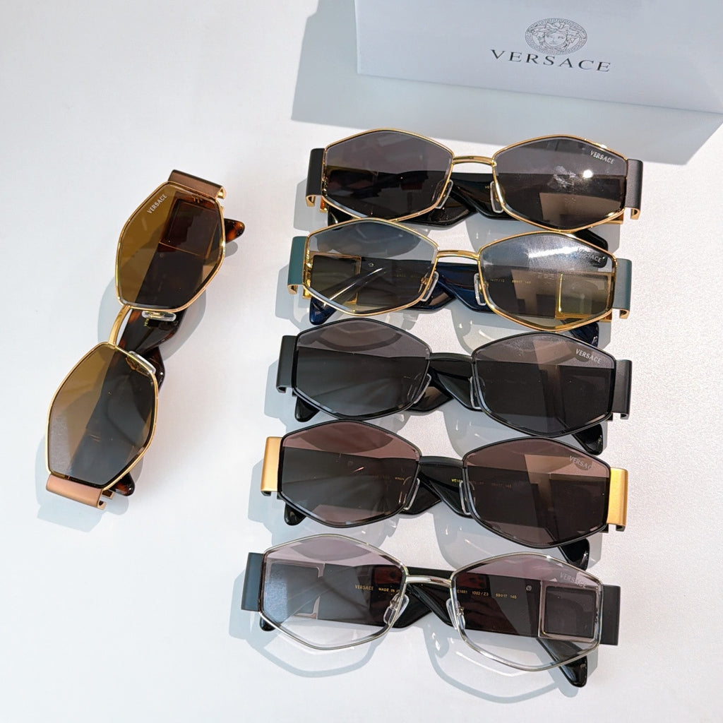 Assorted cat-eye sunglasses set with dark lenses and gold-tone frames, stacked on a box.