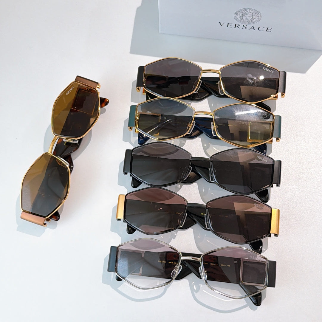 Assorted cat-eye sunglasses set with dark lenses and gold-tone frames, stacked on a box.