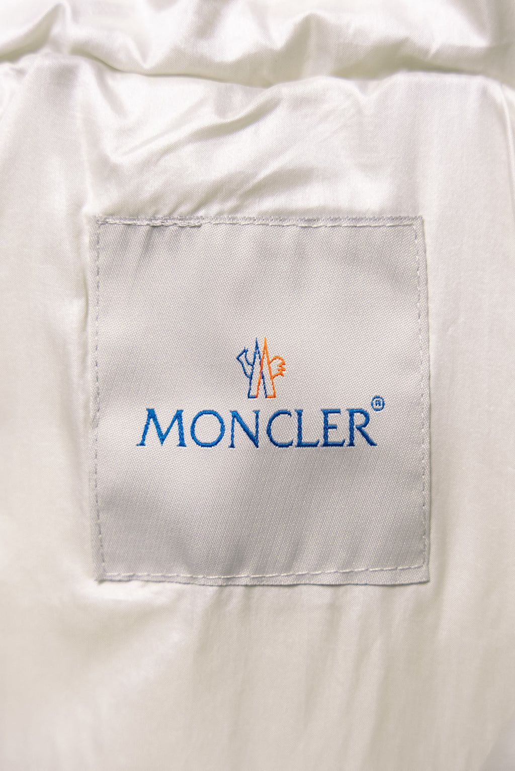 Moncler logo label on white puffer jacket chest pocket