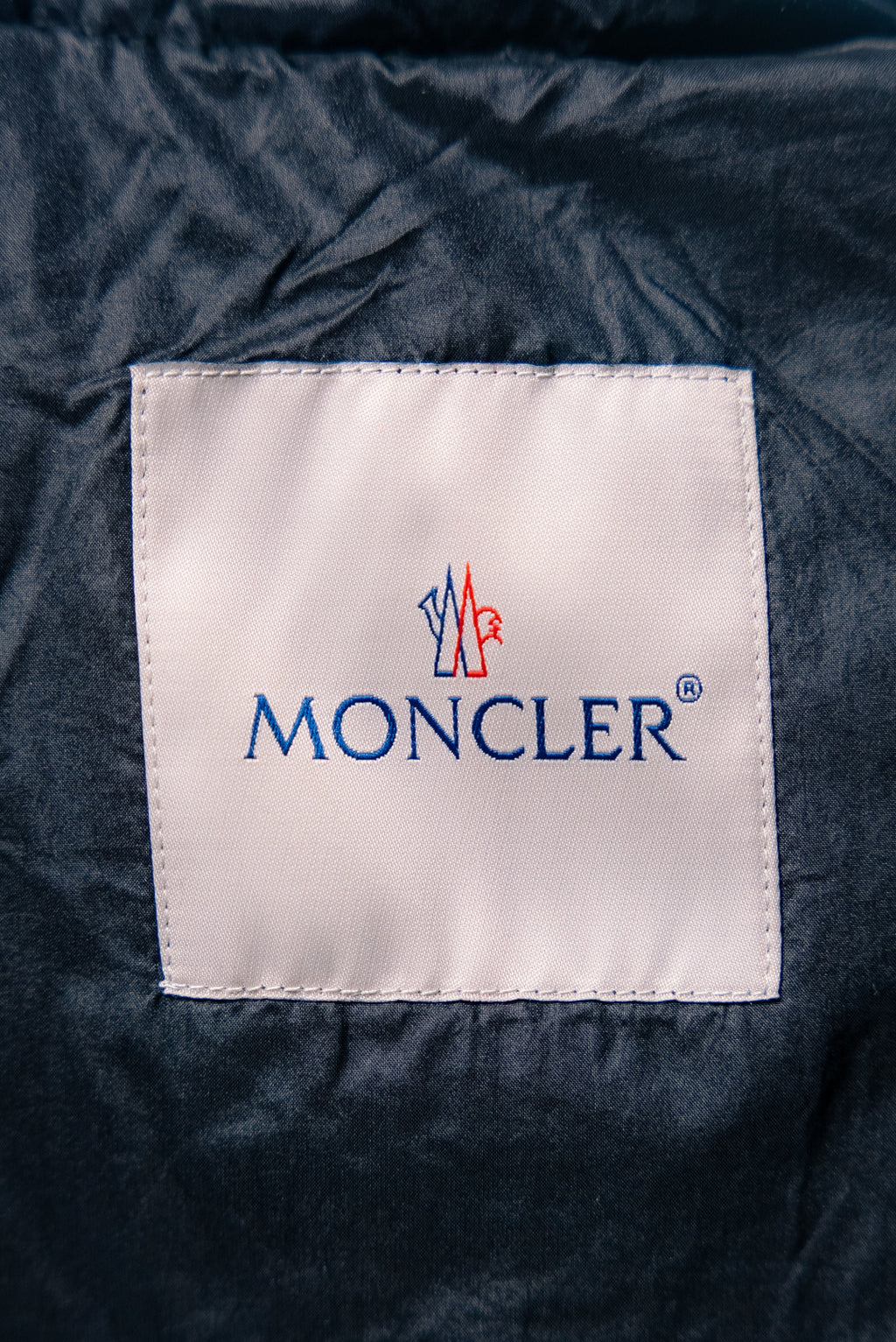Moncler logo fabric label on puffer jacket, square white patch