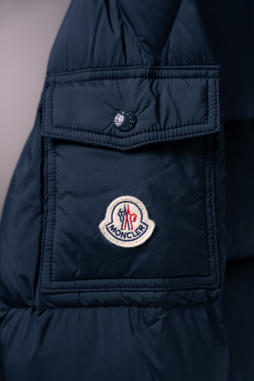 Moncler long puffer jacket chest patch pocket with snap tab and logo badge