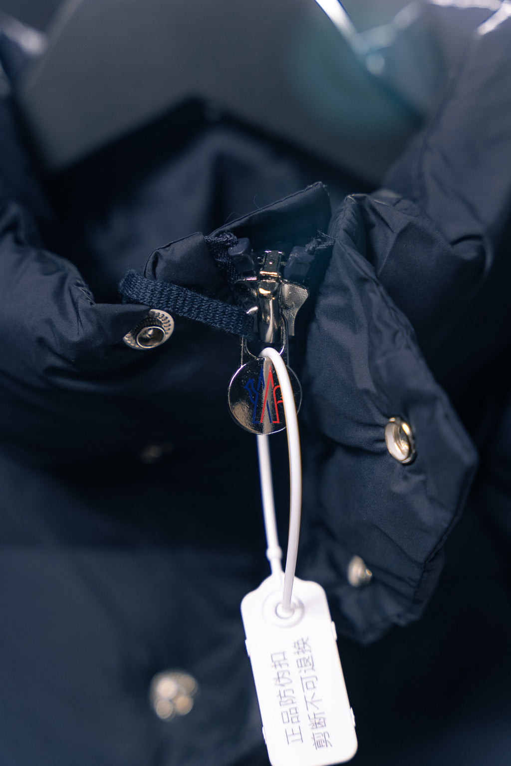 Moncler jacket zipper pull with metal hardware and hanging tag
