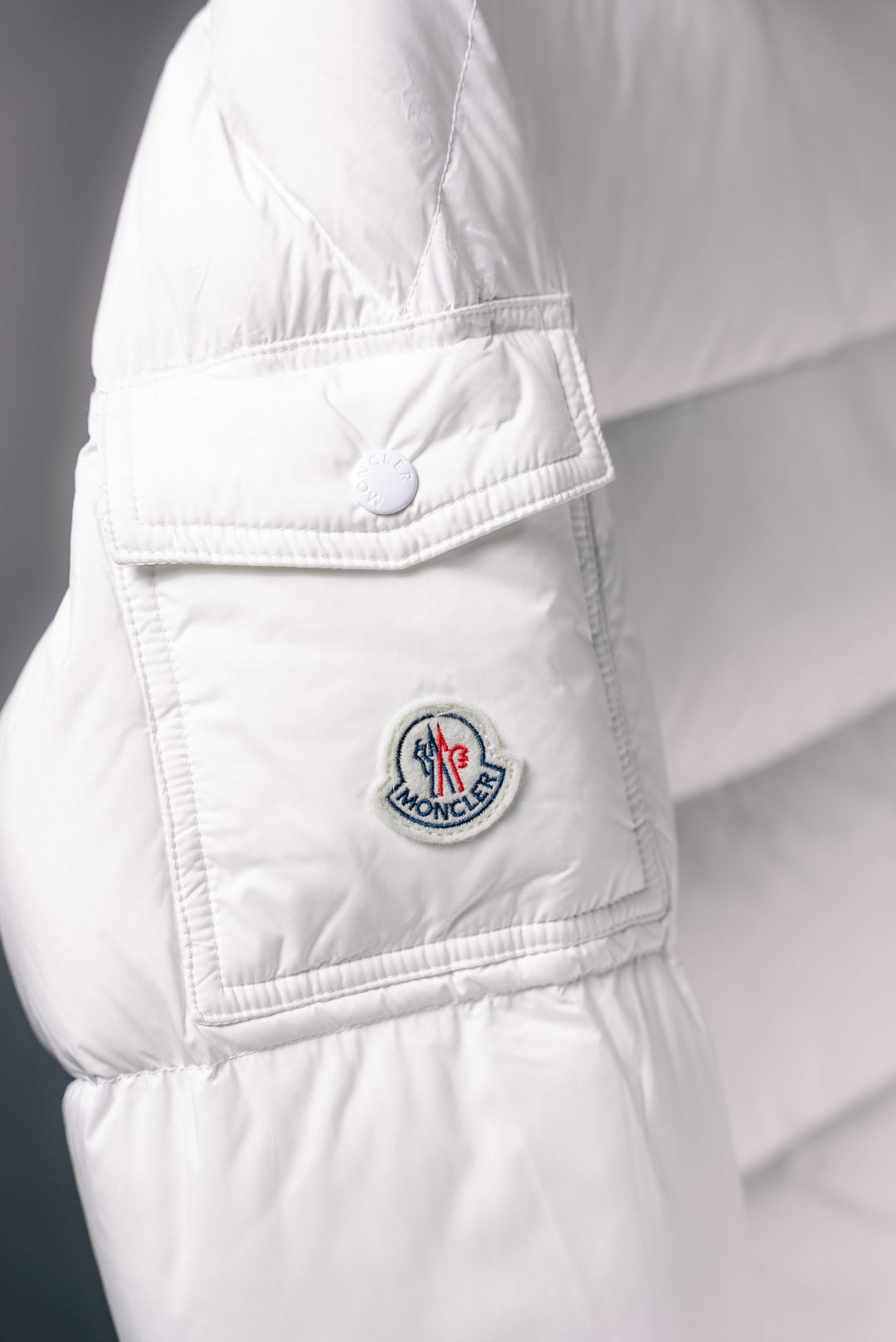 White puffer jacket side pocket with Moncler logo patch and stitched flap