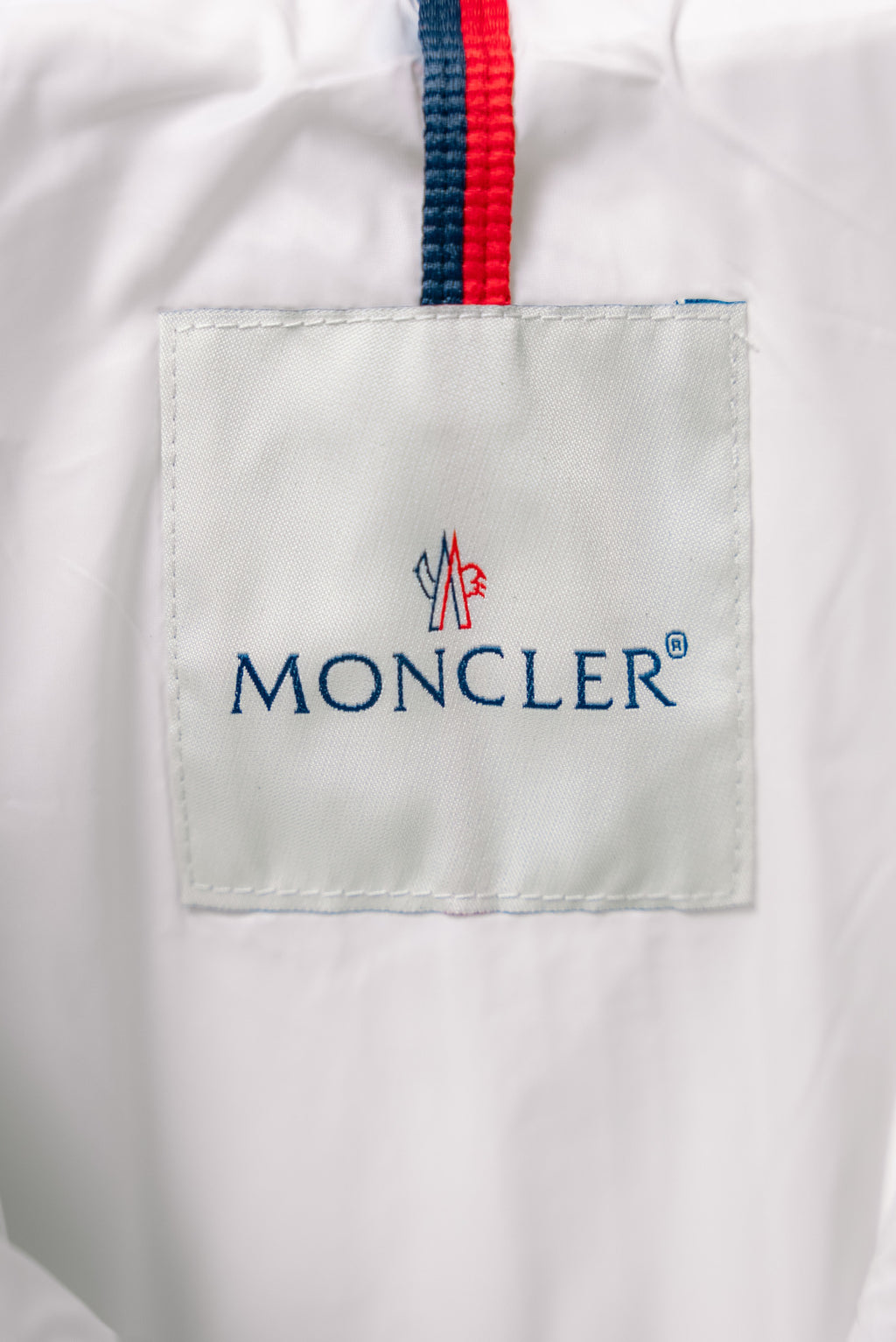 White puffer jacket interior label with blue Moncler logo